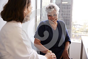 Female Doctor In Office Reassuring Senior Woman Patient And Holding Her Hands