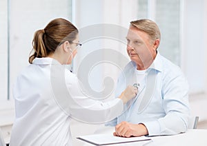 Female doctor with old man listening to heart beat