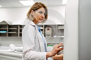 Doctor operating MRI scan using, standing by control panel.