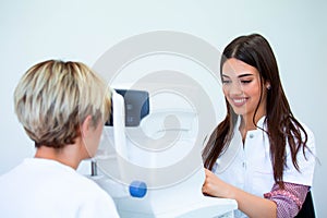 Female doctor ophthalmologist is checking the eye vision of attractive young woman in modern clinic. Doctor and patient in