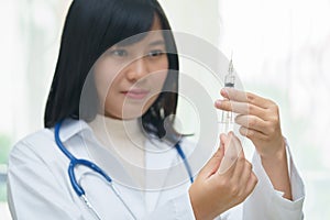 Female doctor or physician holding hypodermic syringe with injection.