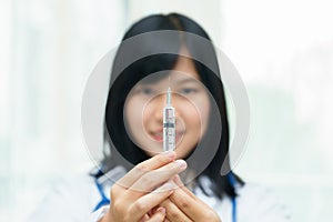 Female doctor or physician holding hypodermic syringe with injection.