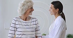 Female doctor physiotherapist helping older 60s grandmother with walking frame.
