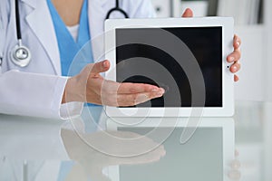 Female doctor pointing into tablet computer, close-up of hands. Physician ready to examine and help patient. Medicine