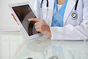 Female doctor pointing into tablet computer, close-up of hands. Physician ready to examine and help patient. Medicine