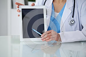 Female doctor pointing into tablet computer, close-up of hands. Physician ready to examine and help patient. Medicine