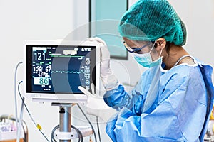 Female doctor pointing to Heart rate monitor in operation room.Healthcare and Medical concept. Hospital and People theme.