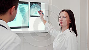 Female doctor points pencil on the x-ray of human head