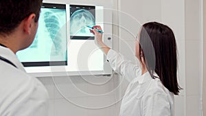Female doctor points pencil on the x-ray of human head