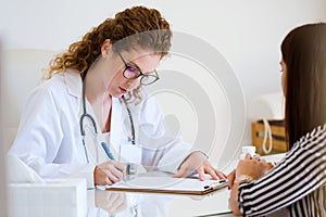 Female doctor prescribing medication for patient in the office.