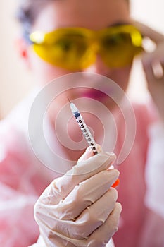 Female doctor in protective glasses and rubber gloves holding open insulin syringe