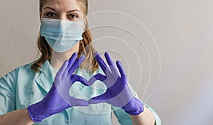 Female doctor in protective gloves making a heart shape symbol with her hands