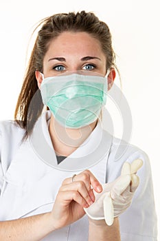 Female doctor puts on gloves plastic wearing protective face mask against coronavirus covid-19