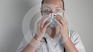 A female doctor puts a protective medical mask on her face.