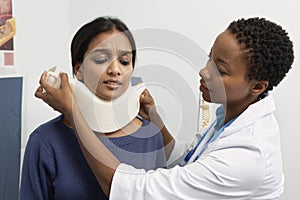 Female Doctor Putting Brace On Patient's Neck