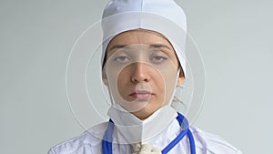 Female doctor is putting off protective blue gloves isolated on white background after some medical manipulations
