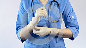 Female doctor putting on rubber gloves, protective uniform, laboratory worker