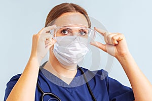 Female doctor putting on surgical face mask and medical goggle