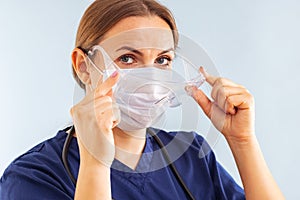 Female doctor putting on surgical face mask and medical goggle