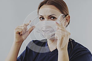 Female doctor putting on surgical face mask and medical goggle