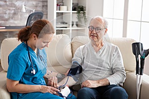 Female doctor reading blood pressure of old man