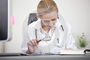 Female Doctor Reading Using Magnifying Glass
