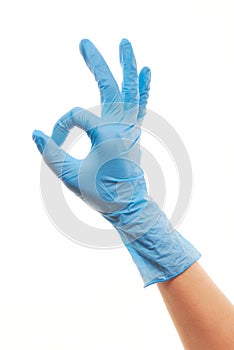 Female doctor's hand in blue surgical glove showing OK sign
