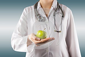 Female doctor's hand holding green apple. Close up