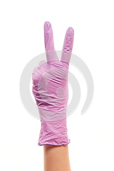 Female doctor's hand in purple surgical glove showing victory sign
