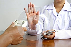 female doctor`s hand refusing to take bribe from patient man at doctor office