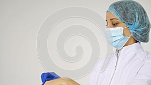 Female doctor's hands putting on blue sterilized surgical gloves in the medical clinic for some medical manipulations