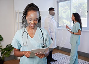 Female doctor in scrubs uses digital tablet with medical team in background