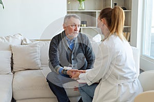 Female doctor senior man taking his blood pressure in doctor office or at home. Old man patient and doctor have