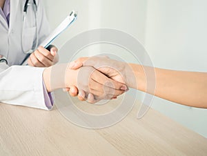 Female doctor shacking patient hand after giving advice or doing health examination or medical checkup in hospital with white