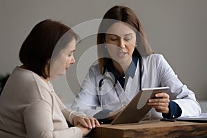 Female doctor show test result on tablet pc to patient