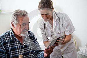 Female doctor showing digital tablet to senior man