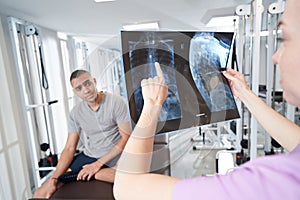 Female doctor showing x-ray scan to man in clinic