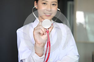 female doctor showing stethoscope for checkup at clinic. physician or medical practitioner holding stethoscope to auscultate photo