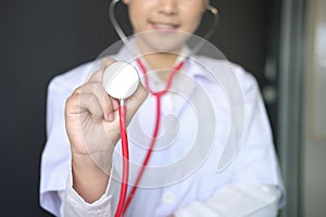 female doctor showing stethoscope for checkup at clinic. physician or medical practitioner holding stethoscope to auscultate photo