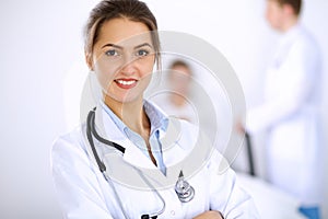 Female doctor smiling on the background with patient in the bed and two doctors