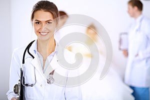 Female doctor smiling on the background with patient in the bed and two doctors