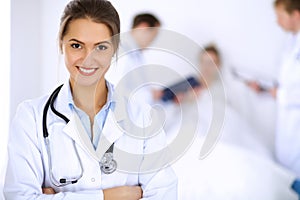 Female doctor smiling on the background with patient in the bed and two doctors