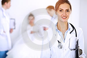 Female doctor smiling on the background with patient in the bed and two doctors