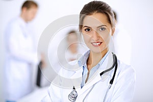 Female doctor smiling on the background with patient in the bed and two doctors