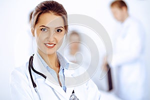 Female doctor smiling on the background with patient in the bed and two doctors