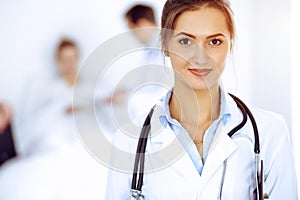 Female doctor smiling on the background with patient in the bed and two doctors