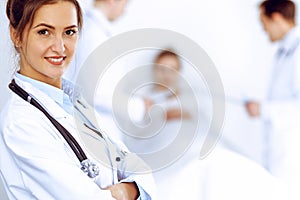 Female doctor smiling on the background with patient in the bed and two doctors