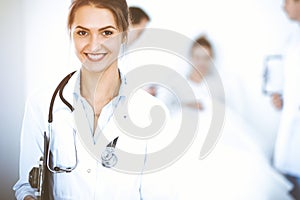 Female doctor smiling on the background with patient in the bed and two doctors