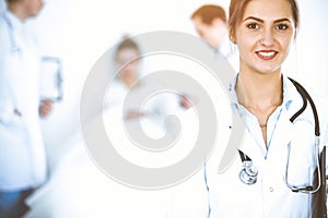 Female doctor smiling on the background with patient in the bed and two doctors