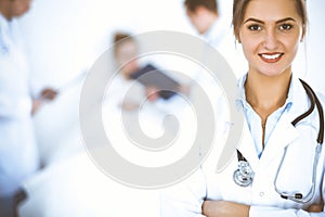 Female doctor smiling on the background with patient in the bed and two doctors